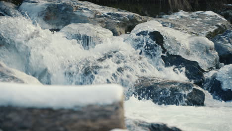 flowing frozen river between big stones, medium shot, slow motion