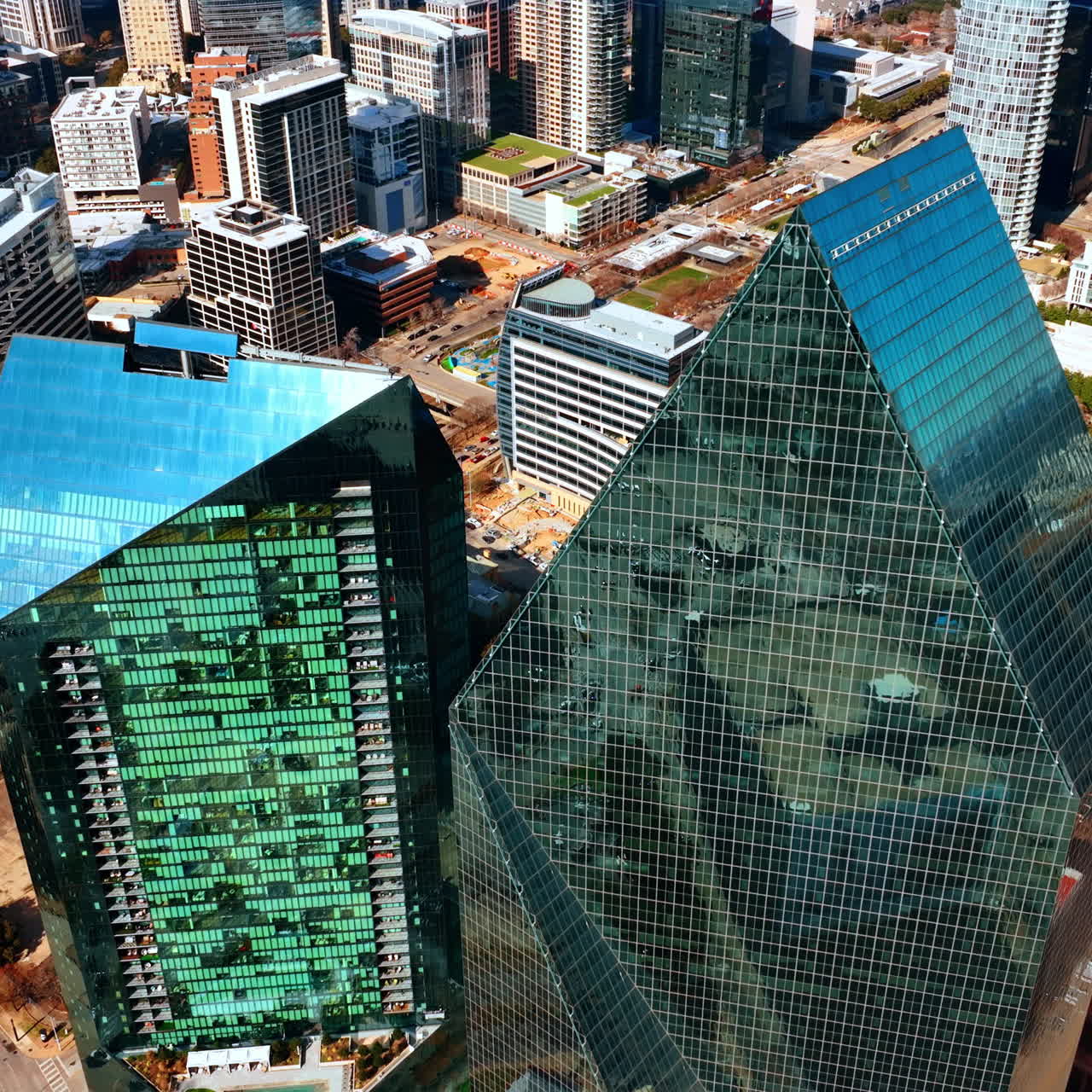 Profili netti dei grattacieli a specchio che riflettono la luce del sole. Riprese con drone sopra gli edifici nella zona alta di Dallas, Texas, USA.