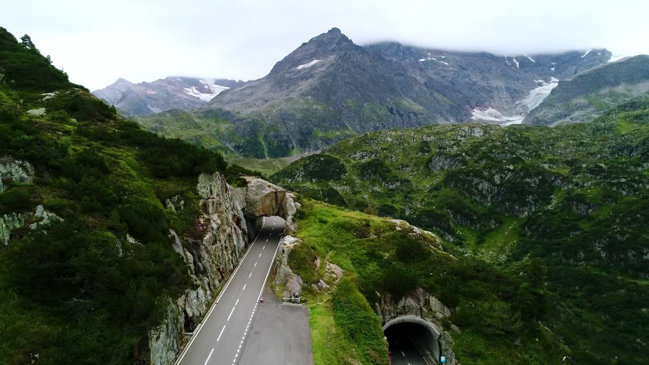 Winding Grimsel Pass road weaving through lush green valleys and steep cliffs