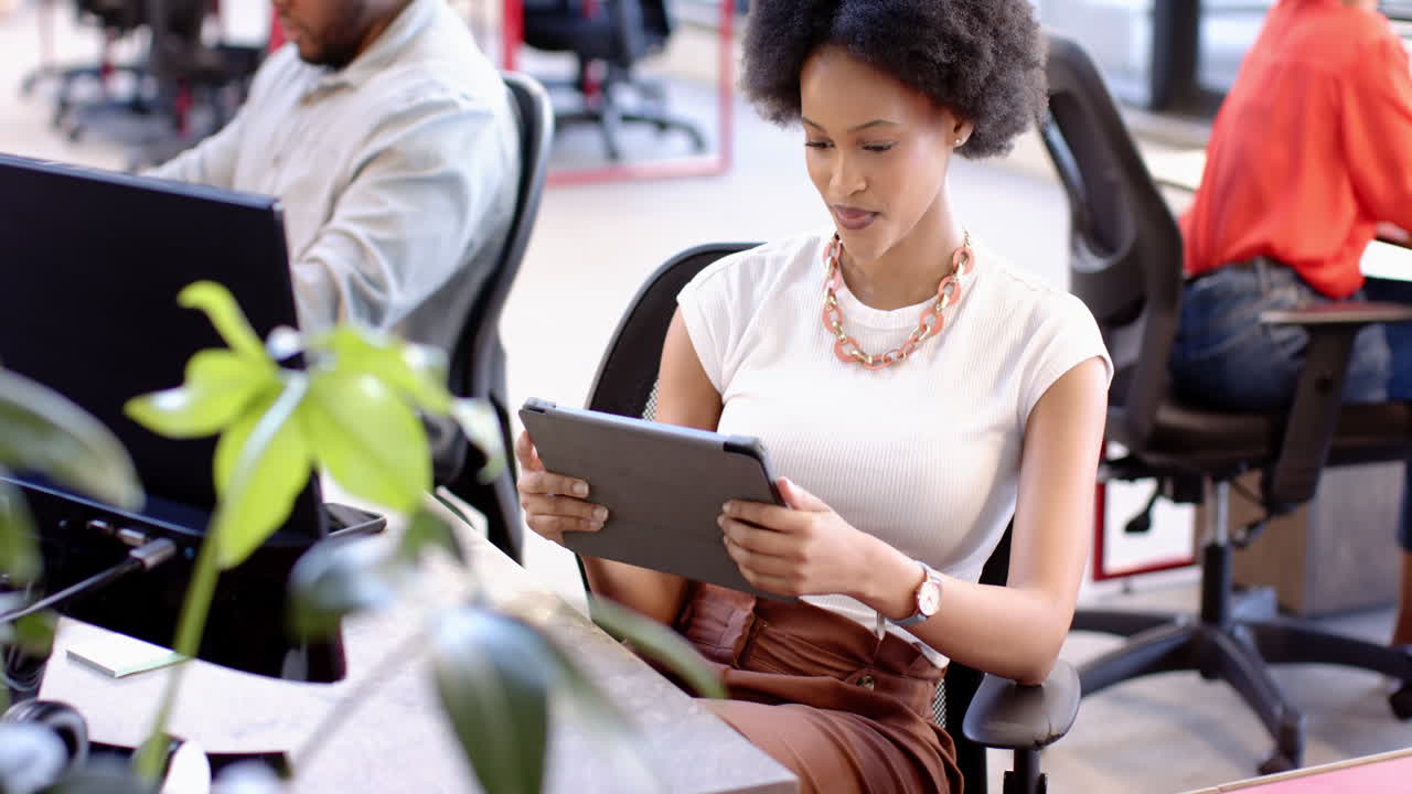 African American woman interacting with tablet in modern office