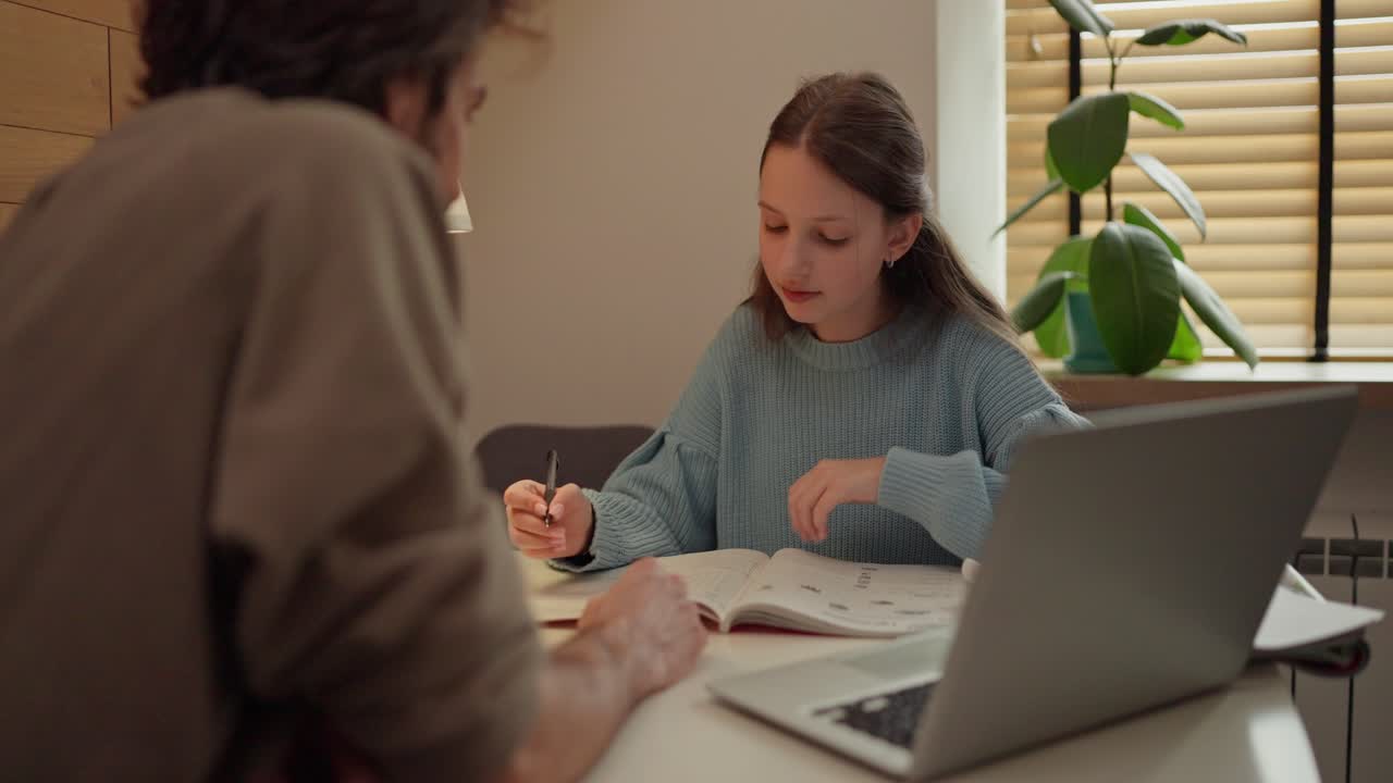 Teenage girl is doing her homework with her father help
