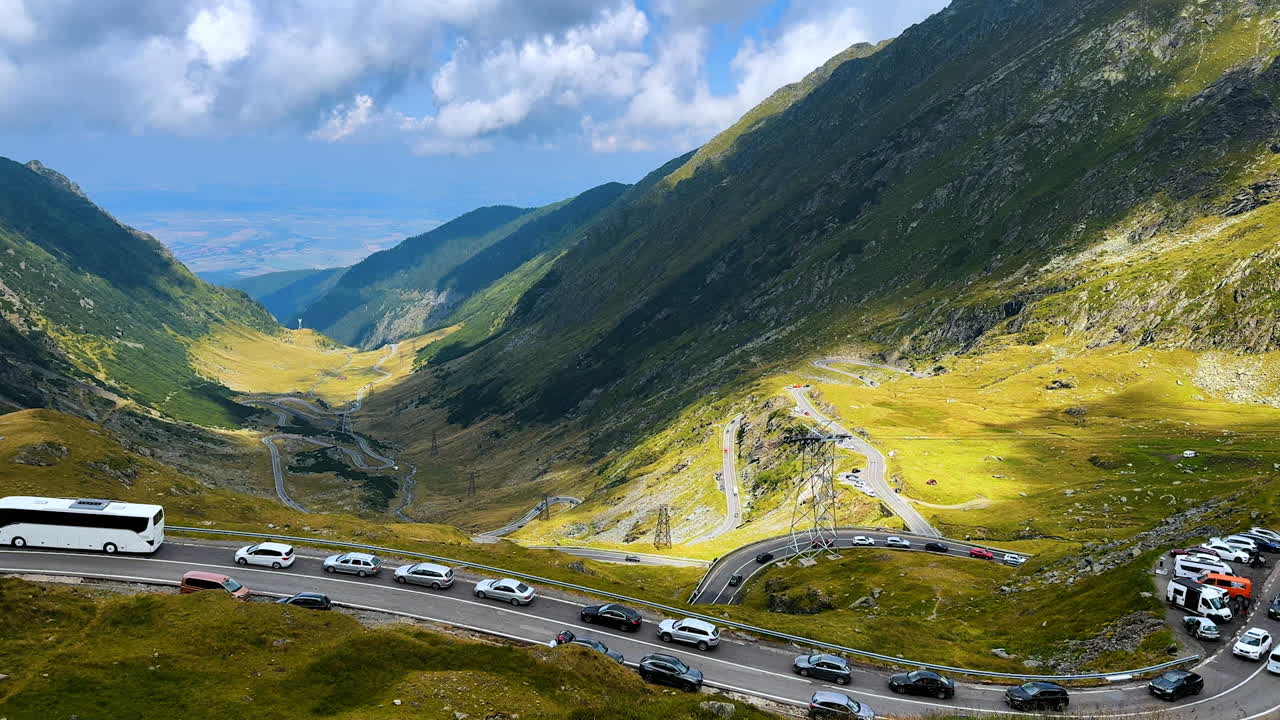 Lots of cars stand on the road in the mountains. Motorway with the observation part on the valley in the mountains crossed by Transfagarash highway
