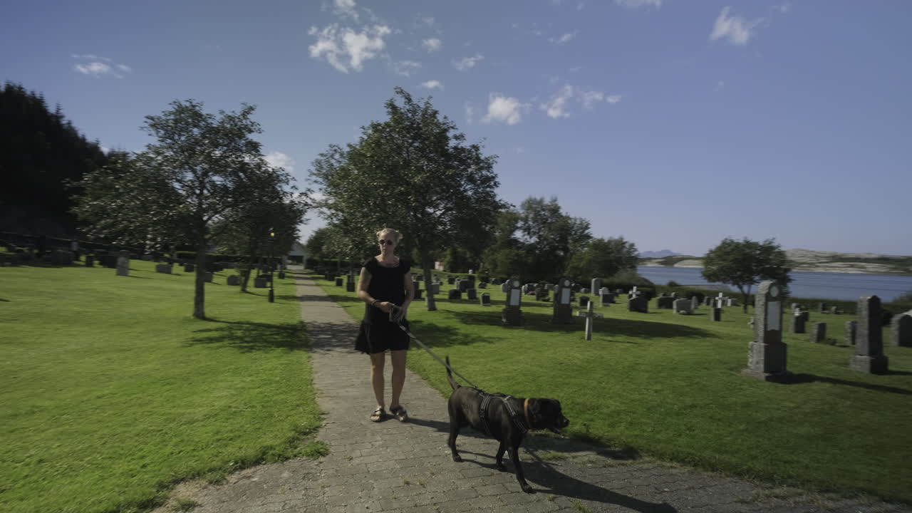 A girl taking a walk with her labrador dog at a graveyard, visiting a beautiful Norwegian church.