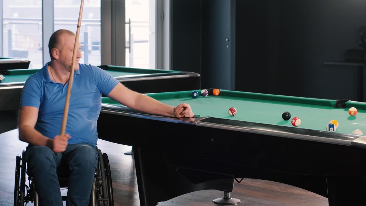 Volwassen mannen met een handicap in een rolstoel spelen biljart in de club
