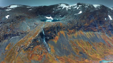 aerial view of a secluded mountain basin with a waterfall tumbling into a winding river surrounded by autumn valley