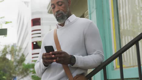 Afroamerikanischer-Mann,-Der-Sein-Telefon-Auf-Der-Straße-Benutzt