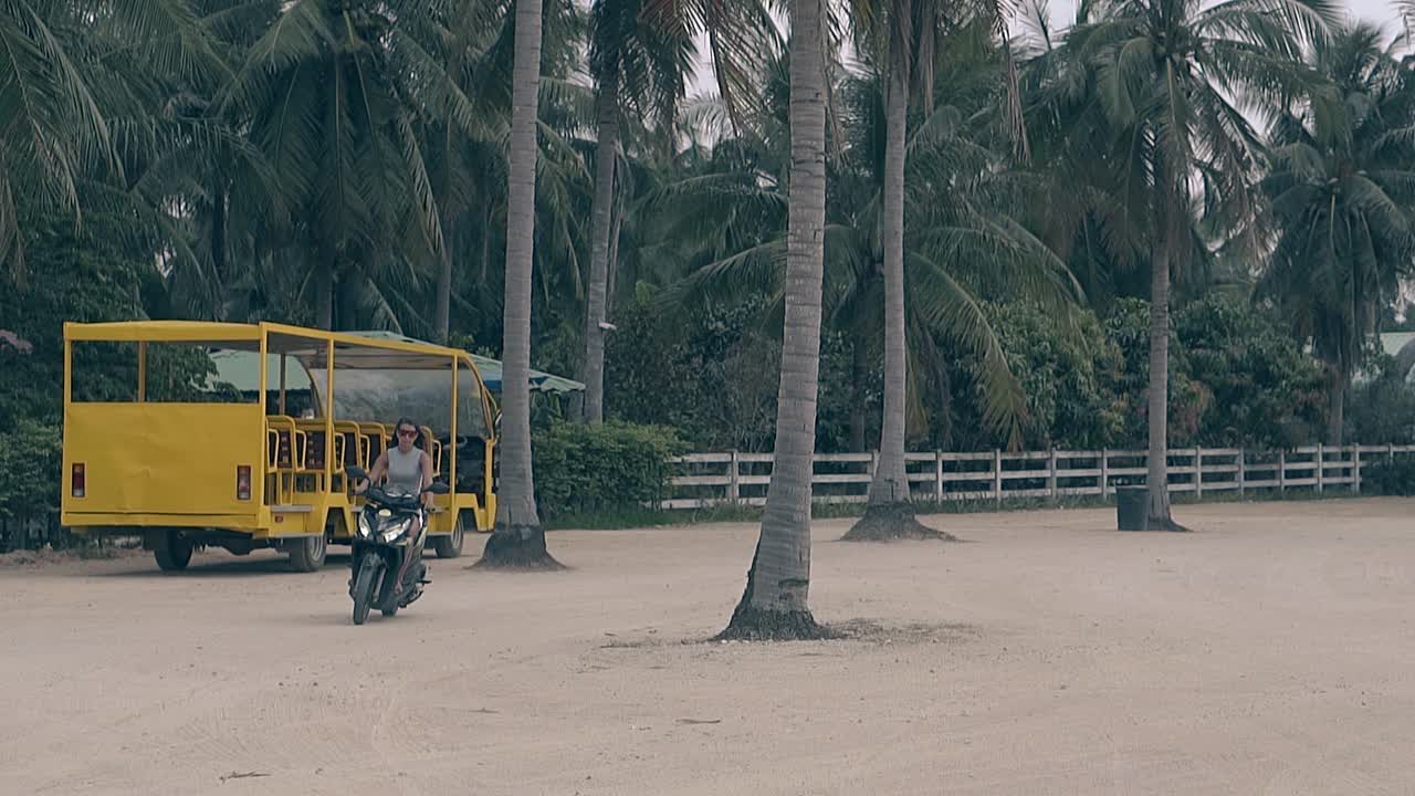 ⁇ 은 여자가 고급스러운 오토바이를 타고 높은 손바닥을 향해 움직입니다.