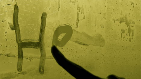 finger writes help on glass in eery green light, close-up