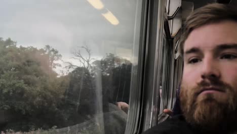 bearded man looks out of the train window