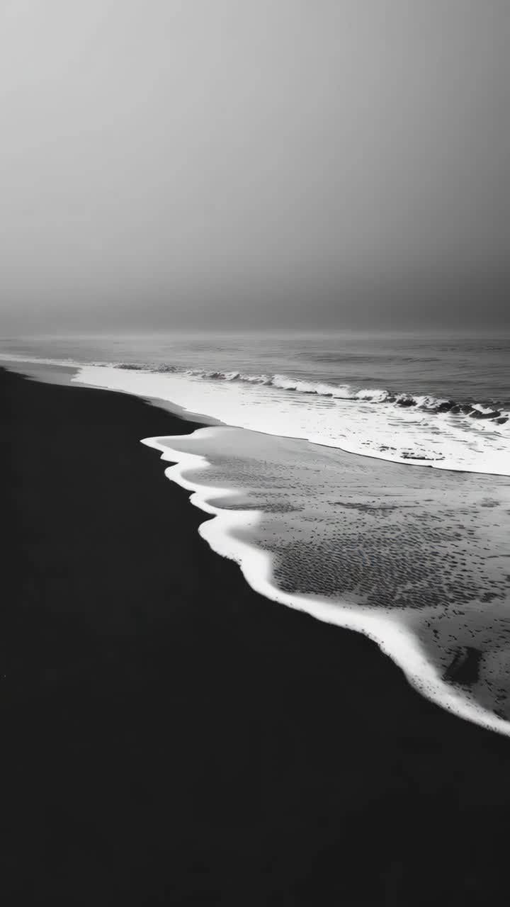 Gambar diam video hitam putih dari pantai yang tenang dengan ombak berbusa