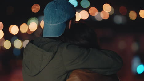 young caucasian couple kissing on rooftop at night enjoying romantic relationship embracing in peaceful urban evening watching beautiful city lights