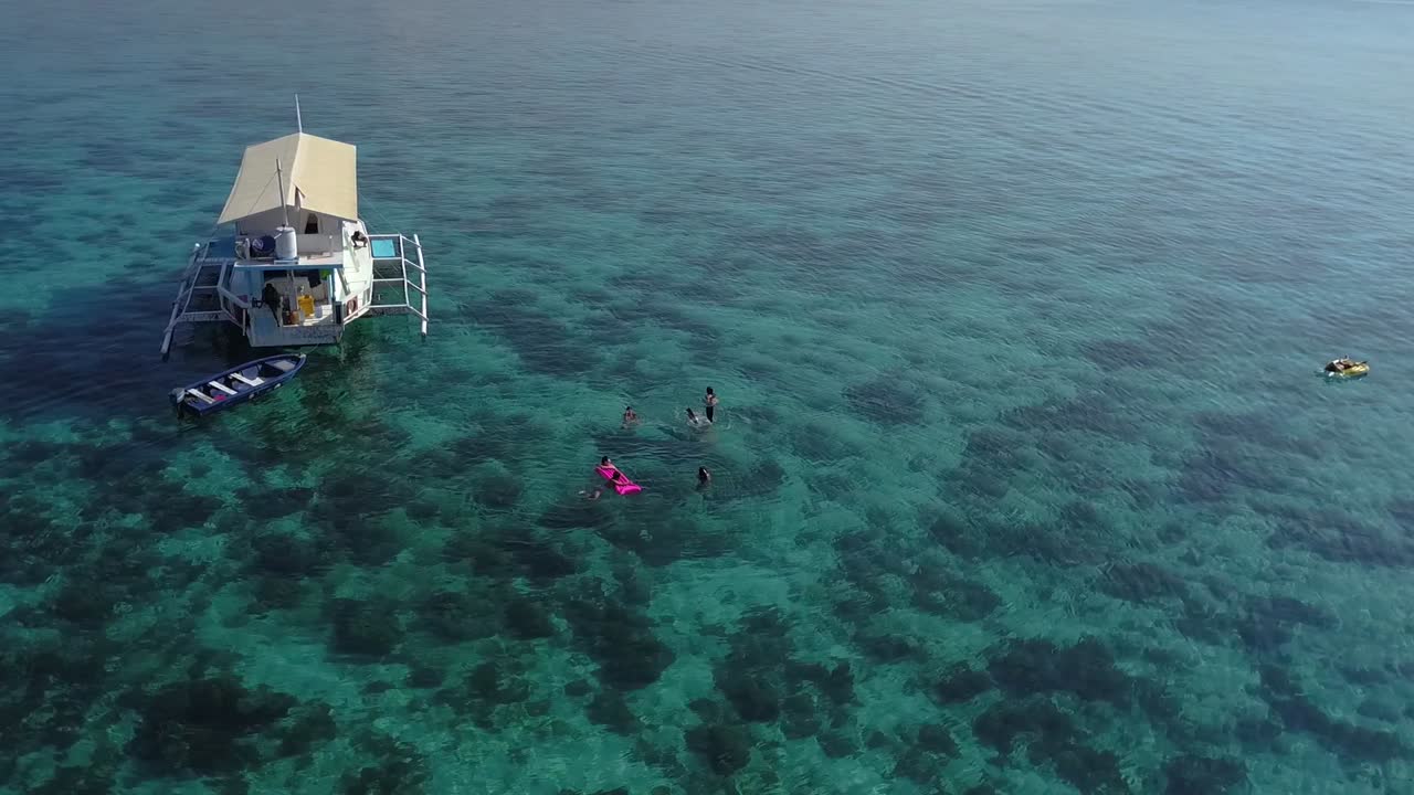 Aerial View of People Swimming near a Houseboat in Turquoise Water