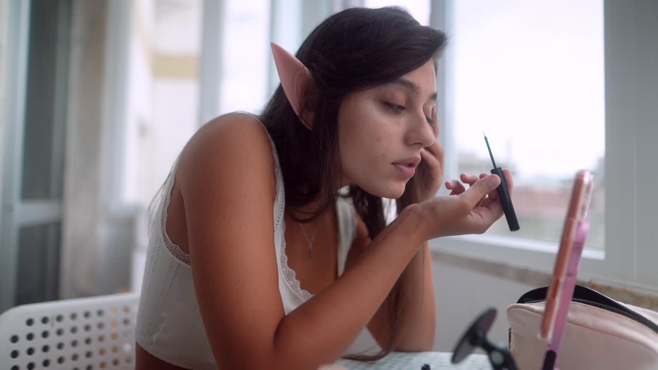 Young Woman with Elf Ears Applying Mascara for Cosplay