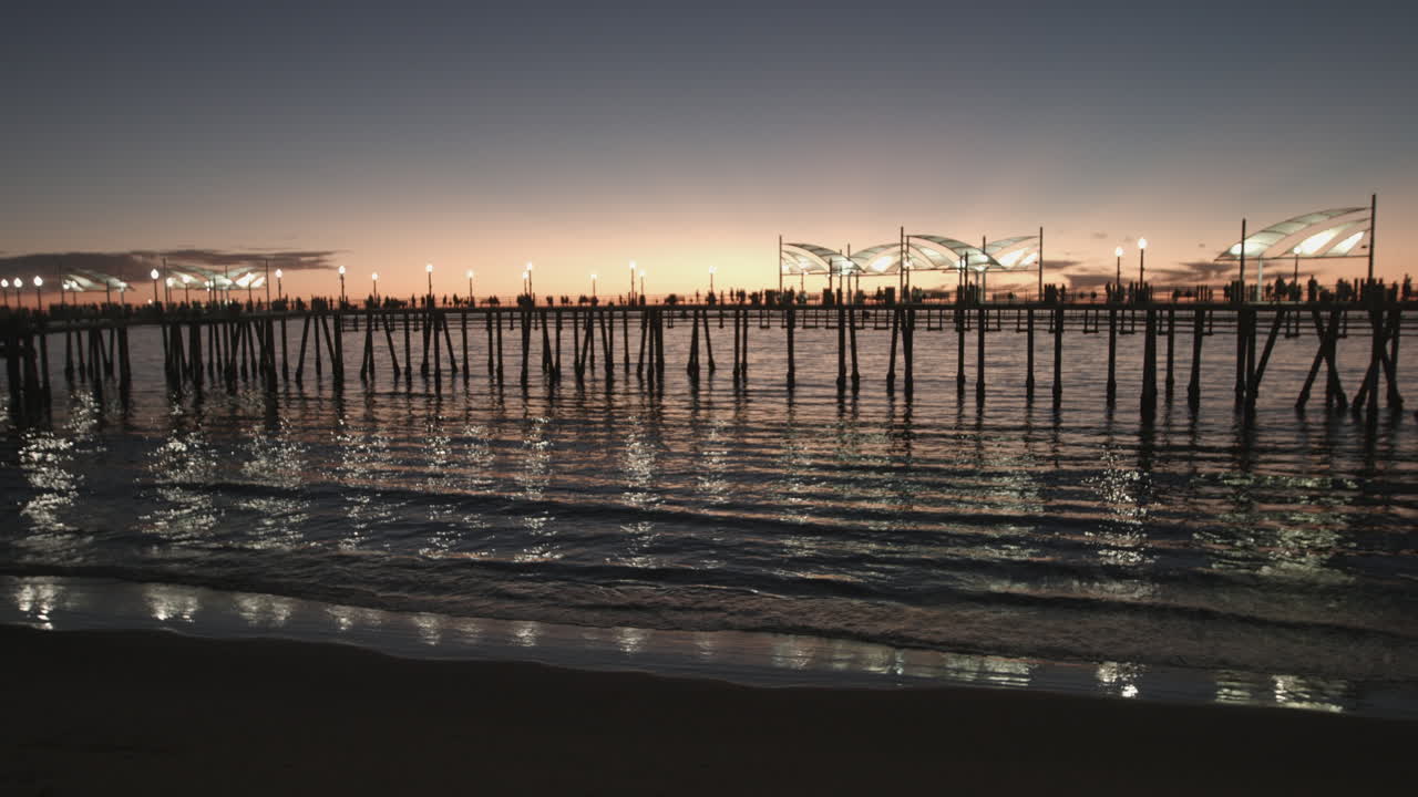 Warm sunset light over the Redondo Beach Pier as people fish and stroll along the waterfront. Golden sky, Pacific Ocean waves, and scenic Southern California coastal atmosphere