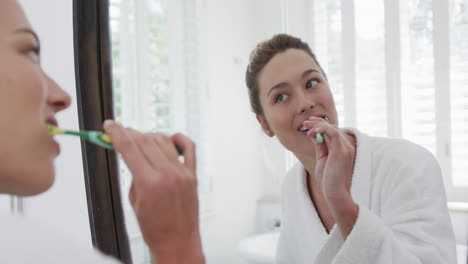 Mujer-Birracial-Cepillándose-Los-Dientes-Mirando-En-El-Espejo-Del-Baño,-Cámara-Lenta