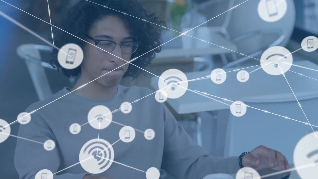 animación de iconos conectados sobre un hombre biracial hablando por teléfono y trabajando en una computadora portátil en cafés.