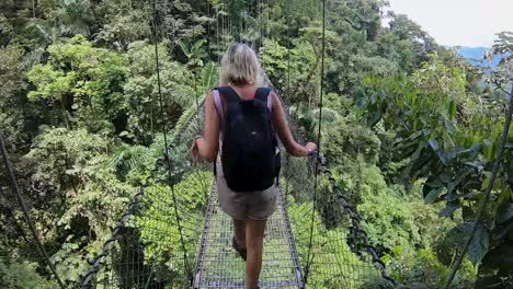 niña cruzando un puente colgante en la selva costarricense