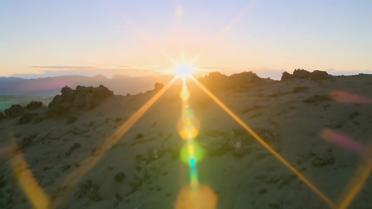 Rising sun with lens-flare column above central rocky ridge casting warm light, revealing river