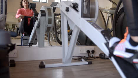 Woman-on-rowing-machine-at-a-gym-in-mirror,-low-angle