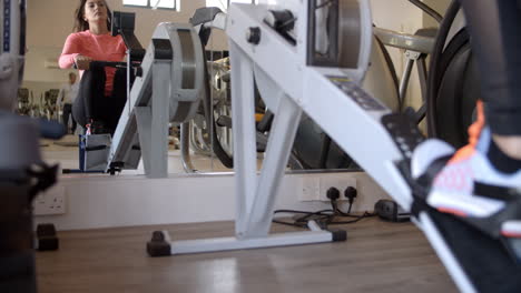 woman on rowing machine at a gym in mirror, low angle