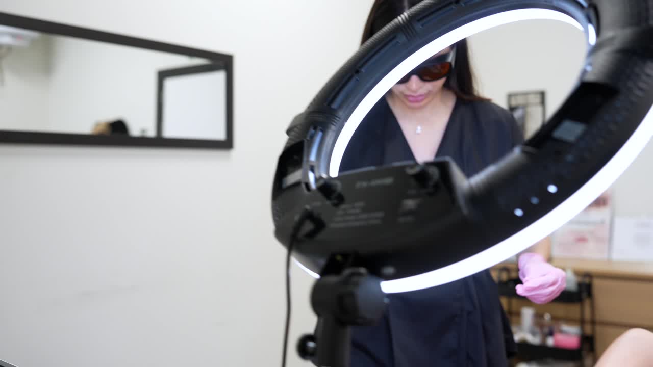 Cosmetologist Prepares Laser Device for Skin Treatment on Client