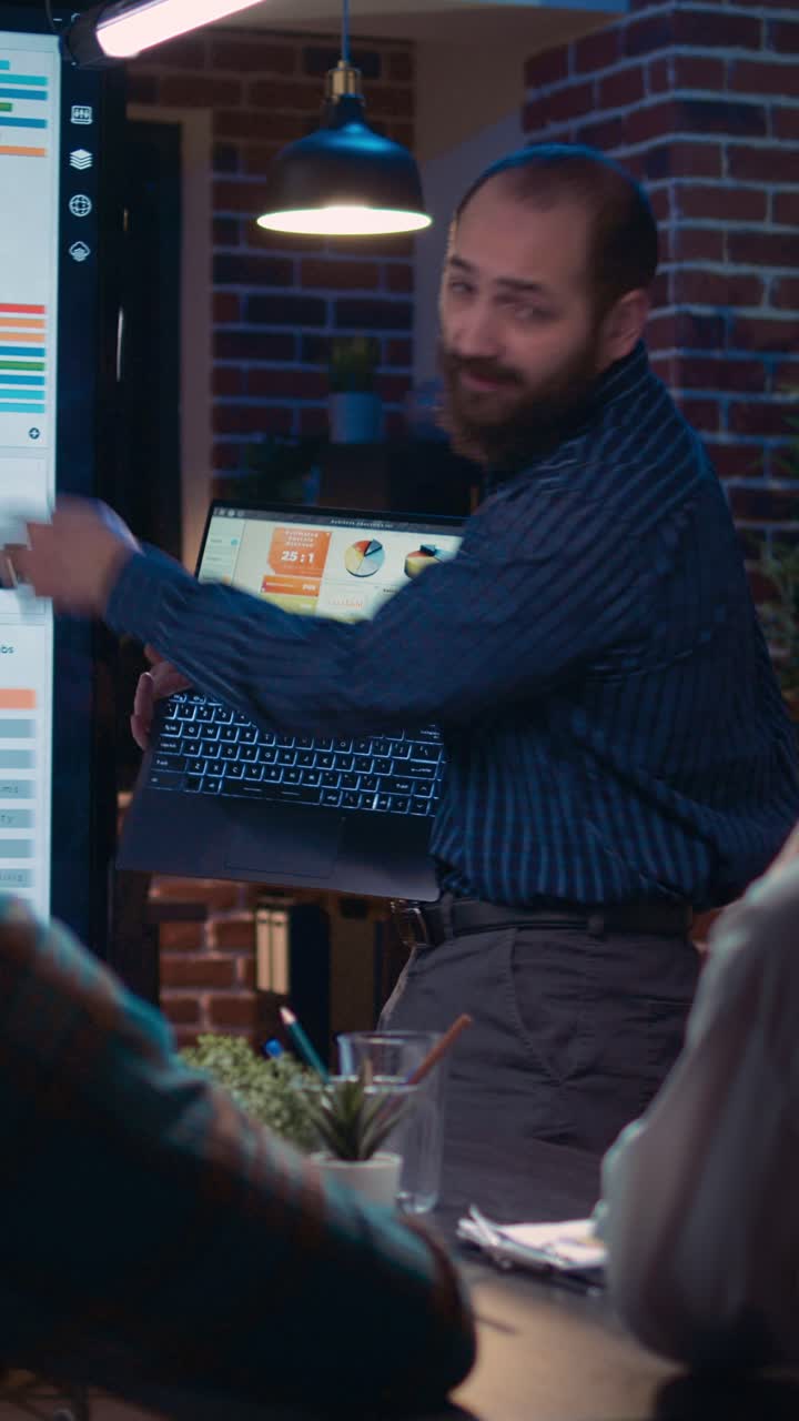 Vertical video: Businessman presenting analytics research, showing statistics on laptop screen