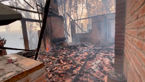 Rauch-Steigt-Aus-Den-Trümmern,-Dem-Verbrannten-Holz-Und-Den-Fliesen-Eines-Hauses-Auf,-Das-Durch-Einen-Flächenbrand-Bis-Auf-Die-Grundmauern-Niedergebrannt-Ist