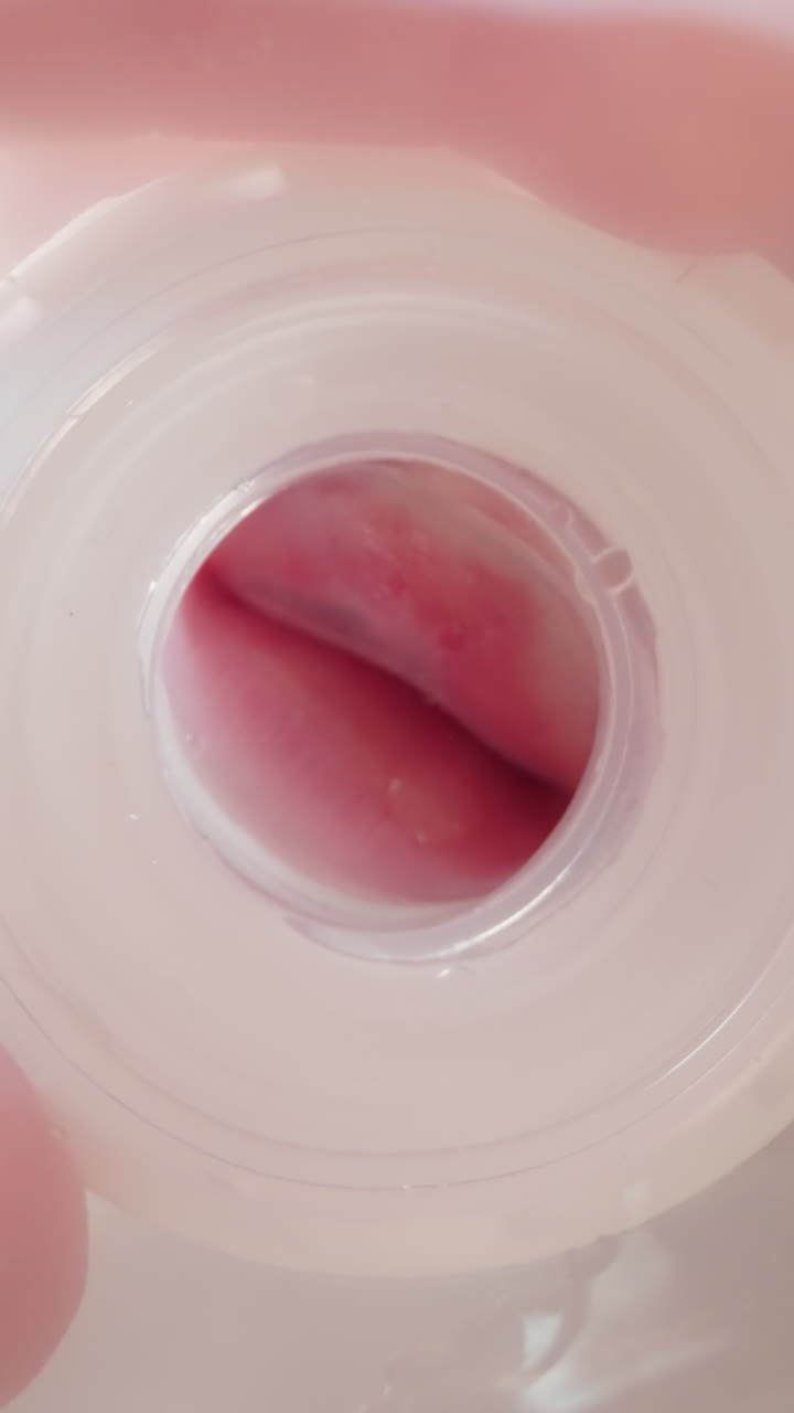 Thirsty little child holds bottle with fingers and squeezes and spreads rubber nipple with lips. Toddler puts down empty bottle macro low angle shot