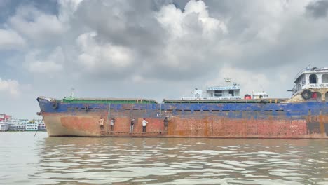 tracking-shot-of-five-workers-hammering-the-hull-of-a-docked-rusty-ship-in-Sylhet