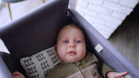 caucasian baby lies in the cradle waved by a parent. stubborn kid doesn't want to fall asleep.