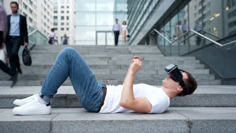 man immersed in virtual reality while lying on city stairs