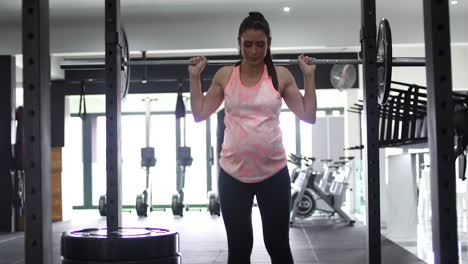 imágenes de una modelo embarazada haciendo sentadillas en un gimnasio tratando de mantenerse en forma en su cuarto trimestre.