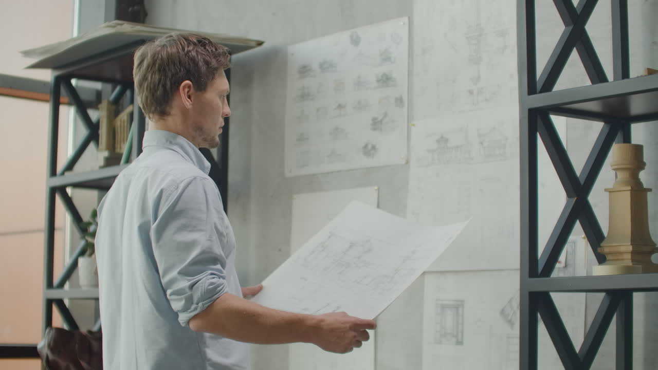 oficina elegante en estilo loft: pared de ladrillo con notas y planos. dibujos de futuros edificios casa modelo en la pared. diseñador trabaja en oficina loft