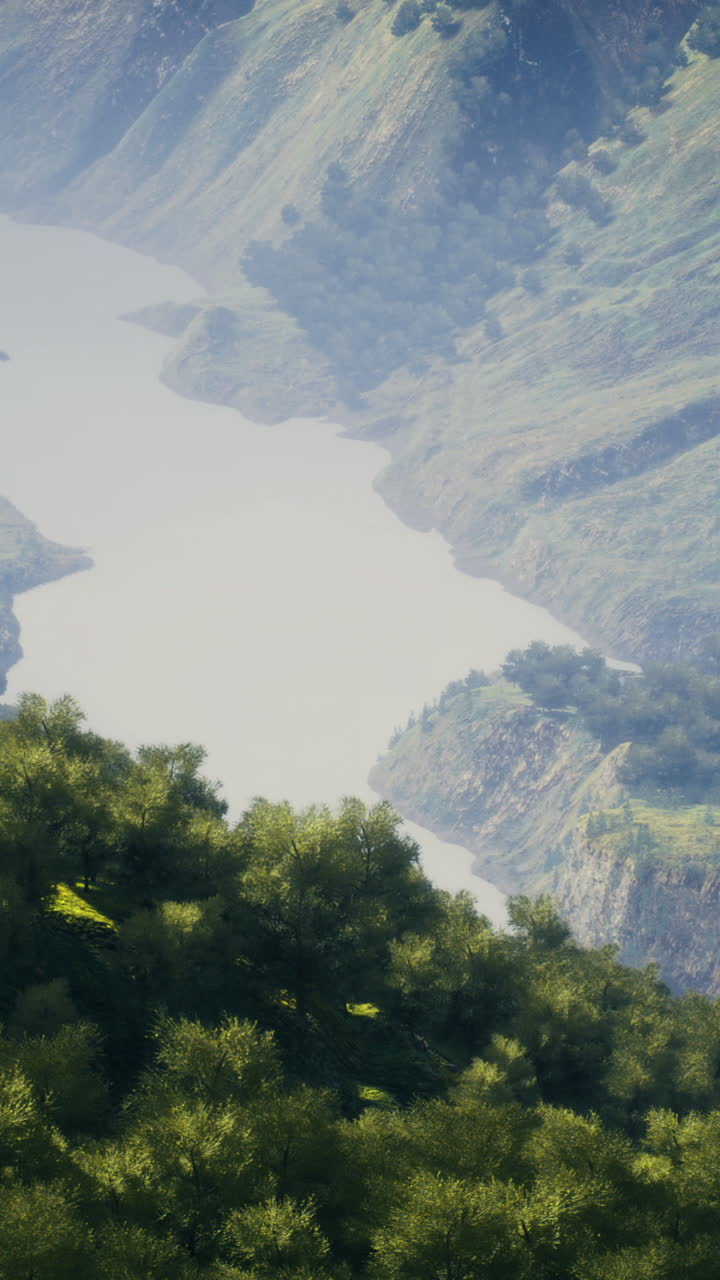 Fiume calmo che serpeggia tra montagne verdi e lussureggianti in un pomeriggio sereno