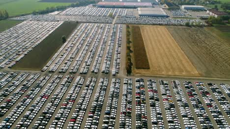 aerial footage of finished cars ready to be shipped on huge distribution center