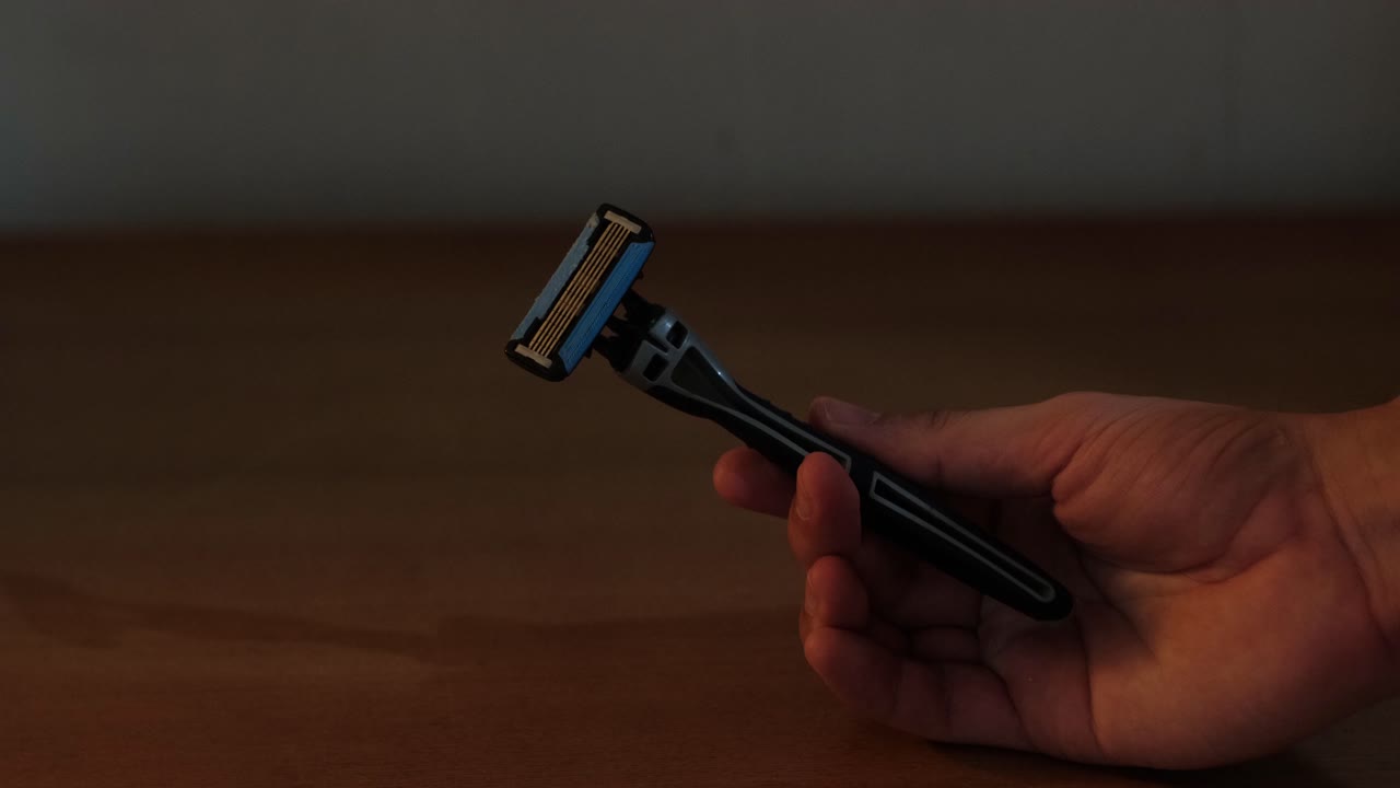 Close-Up Static Shot of a hand holding a safety razor in an indoor setting for hygiene, shaving, and men's grooming