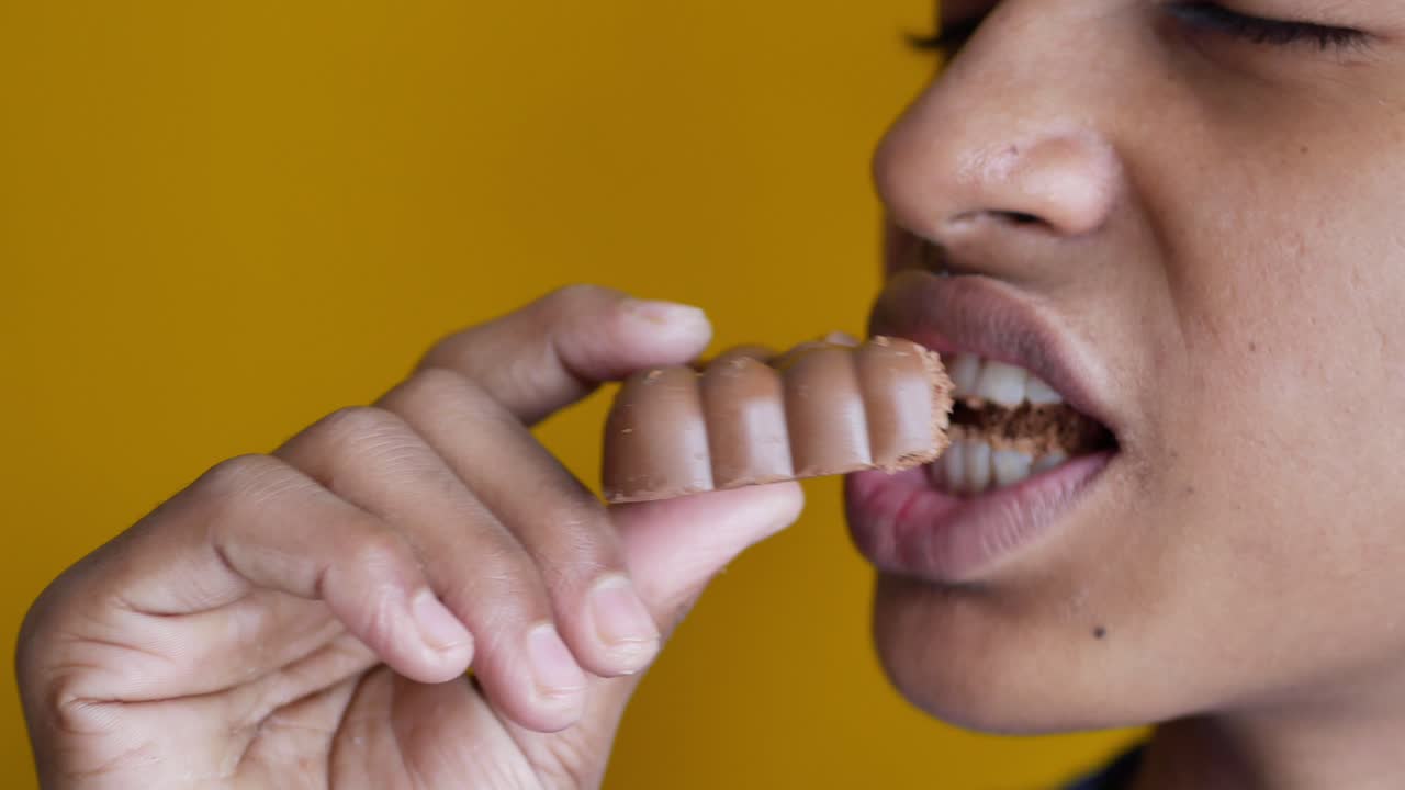 Ragazzo che mangia cioccolato fondente in primo piano