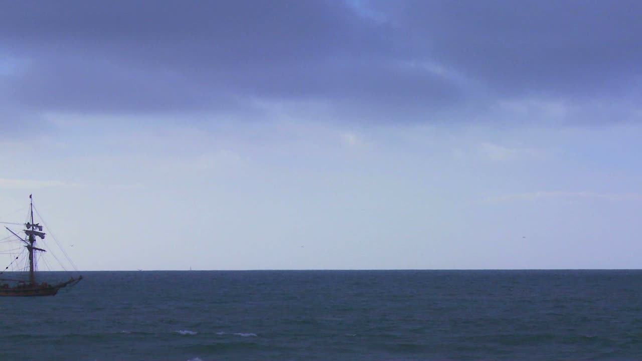 큰 돛대가 달린 배가 돛을 펼치지 않고 바다를 항해한다