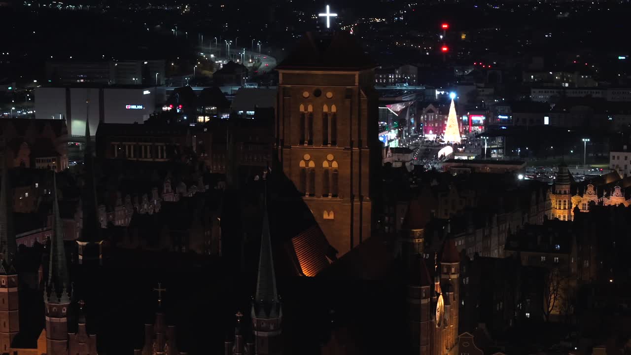 Aerial orbit shot of historic lighting St. Mary Church in Gdansk City at night. Poland, Europe during christmas season. Old town with old buildings in downtown. Wide shot