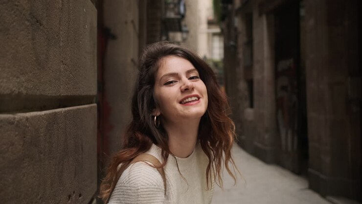 joven enviando un beso en el aire a la cámara en una calle estrecha