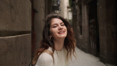 young woman sending air kiss to camera on narrow street