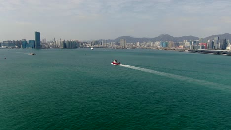 Small-Offshore-supply-ship-roaring-across-Hong-Kong-bay,-Aerial-view