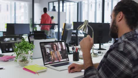hombre de oriente medio teniendo una videollamada con una colega en una computadora portátil en la oficina