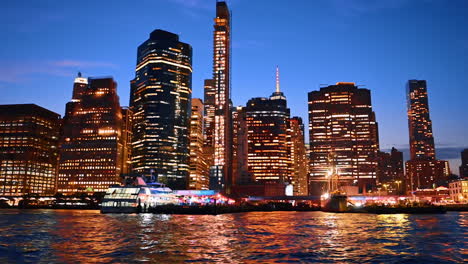 varied high-rise buildings in the luminous skyline of new york. boat tour along the stunning waterfront at night
