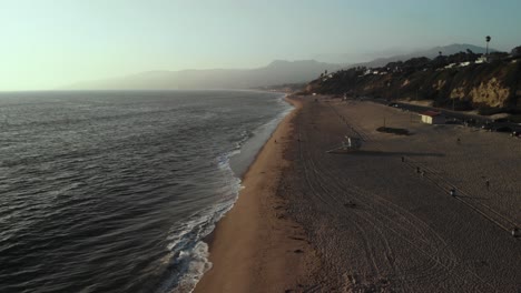 Una-Toma-Aérea-Con-Vistas-A-Una-Playa-Cerca-Del-Acantilado-De-Point-Dume-En-Malibu-En-California-En-La-Noche-Como-Las-Puestas-De-Sol