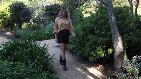 young woman walks through flower garden sitting on park bench slow motion