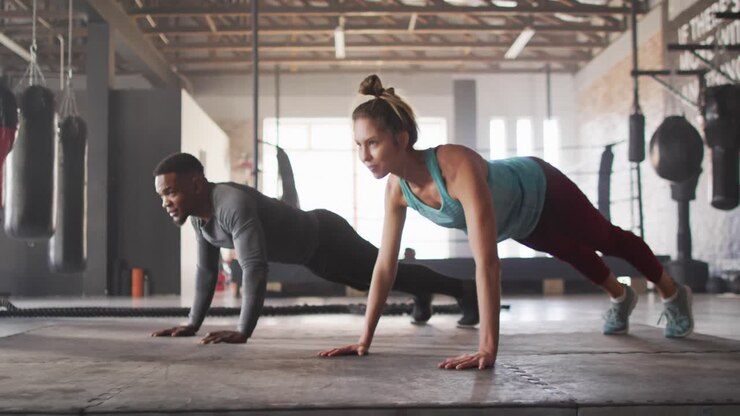 Video of diverse fit man and woman doing push ups at gym