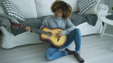 mujer joven tocando la guitarra en casa