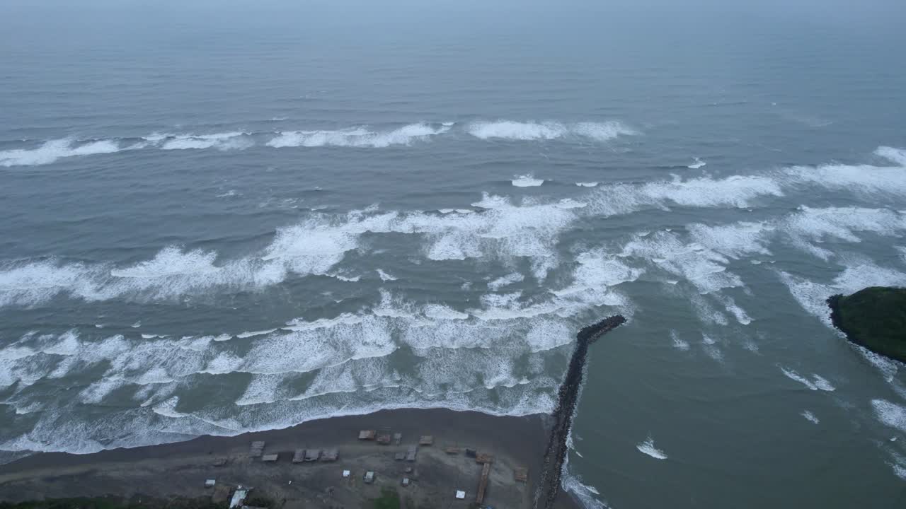 Drone footage in jib down with view of function of breakwater and waves approaching to coast in Barra de Sontecomapan Veracruz Mexico