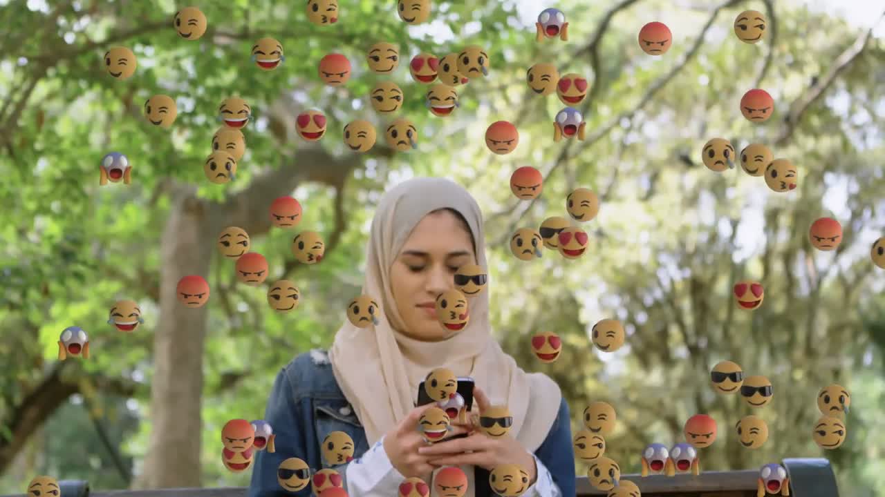 스마트폰을 사용하여 히자브를 입은 여성 위에 떨어지는 이모티콘의 애니메이션